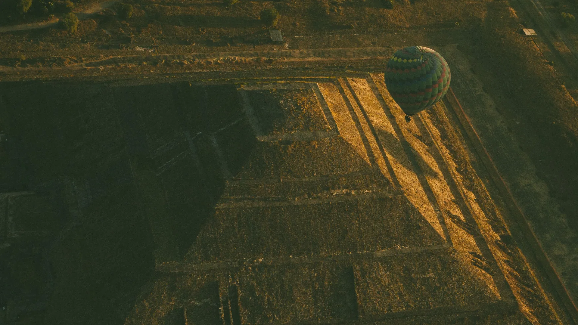 Horkovzdušný balón stoupající při východu slunce nad pyramidami v Teotihuacánu
